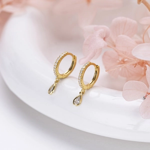 Macro view of gold hoop earrings with water drop pendants and sparkling zircon stones