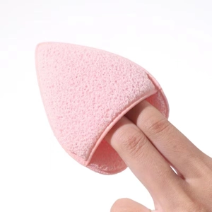 Close-up of pink triangular exfoliating sponge mitt worn on fingers for facial cleansing