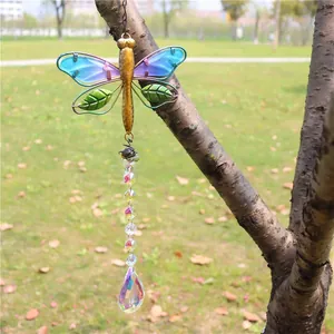 Detail of dragonfly crystal suncatcher with golden wings and blue pendant on a tree