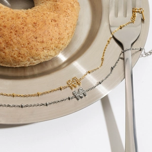 Elegant gold and silver titanium steel bracelets with rhinestone M pendant on a plate