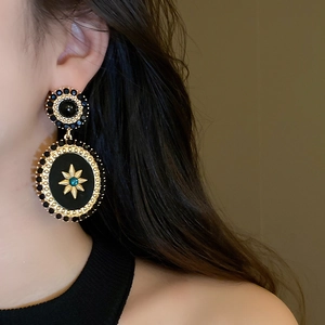 Detail of vintage oval pearl earrings with gold star motif and black resin finish