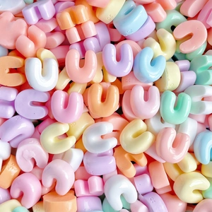 Macro shot of colorful resin alphabet charms in assorted pastel tones for DIY crafts