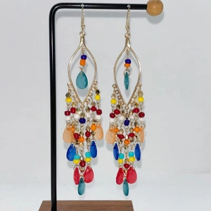 Detail of colorful bohemian beaded tassel earrings with multi-layered design and gold hooks