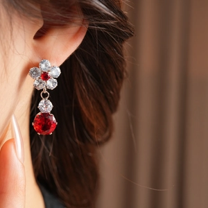 Detailed macro view of zircon flower drop earrings with red stones in rose gold setting