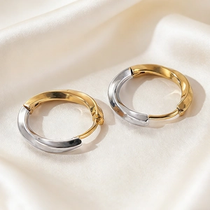 Detail shot of two-tone gold and silver stainless steel hoop earrings on silk fabric