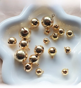 Detailed view of polished gold round bells in various sizes for DIY jewelry and crafts