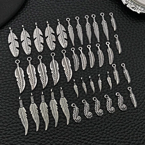 Close-up of vintage alloy feather pendants in various sizes on black leather texture
