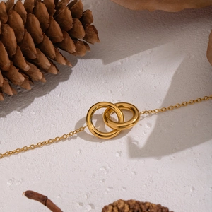 Detail of gold interlocking circles bracelet on rustic background with pinecone
