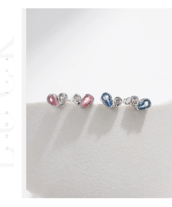 Macro detail of asymmetric heart-shaped S925 silver studs in pink and blue contrast colors
