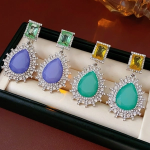 Détails macro de boucles d'oreilles de luxe en cristal violet et vert avec oxydes de zirconium