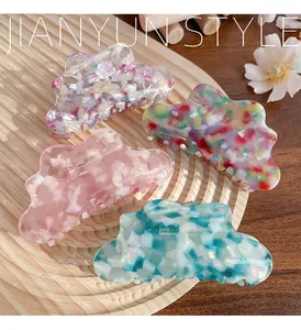 Cloud-shaped acetate hair claws with marble texture patterns on a wooden display