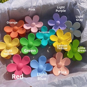 Flat lay of twelve colorful matte daisy hair claws with petal shapes in a gift box