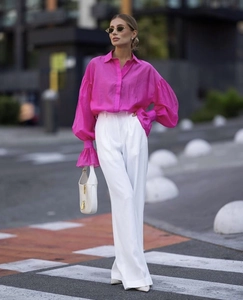 Detail of pink long-sleeve chiffon blouse with puff sleeves and white wide-leg trousers