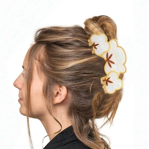 Floral hair claw clip in pearl white and gold finish shown on model hairstyle