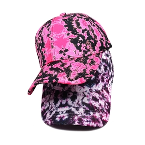 Detail of two tie-dye baseball caps in vibrant pink, purple and black patterns