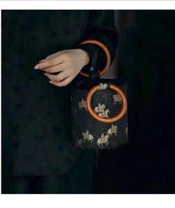 Detail of vintage bucket bag with wooden ring handles and Chinese tapestry horse pattern