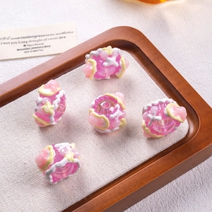Close-up of five pink translucent DIY resin beads with colorful oil-painted accents