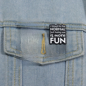 Detail of four creative enamel brooches with text slogans pinned on denim jacket pocket