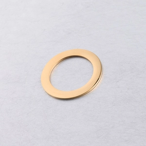 Close-up of a 35mm golden polished stainless steel ring pendant on a gray textured paper