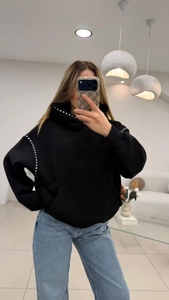 Close-up of black hooded sweatshirt featuring silver stud rivets on the shoulders