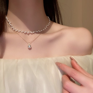 Gros plan d'un collier de perles double couche avec chaîne dorée sur mannequin élégant