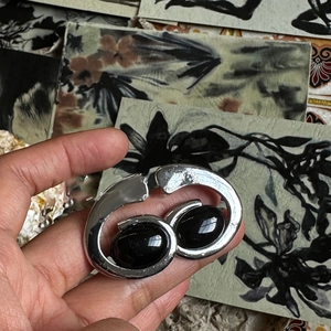 Close-up of irregular silver metal collar featuring two large oval black resin pendants