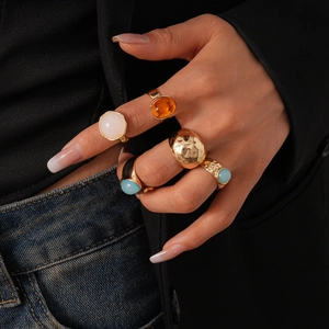Close-up of five-piece gold metal resin geometric rings set worn by a model