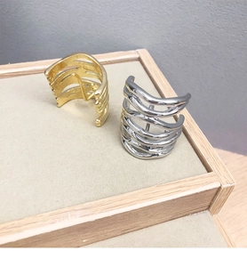 Detail of gold and silver multi-layer ear cuffs on a beige jewelry display tray