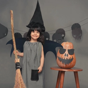 Detailed kids Halloween witch costume with black bat wings, hat, and grey dress with broom