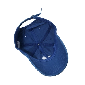Detail of blue cotton baseball cap interior showing adjustable strap and 100% cotton label