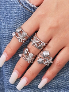 Detail of silver starfish and shell rings with micro-pave zircons on denim background