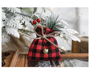 Detail of buffalo plaid Christmas gift bag with pine needles, berries, and gold bell