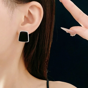 Gros plan d'une boucle d'oreille trapèze en résine avec bord argenté sur un mannequin
