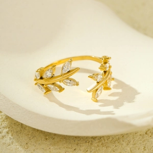 Golden leaf open ring with marquise zircon stones on a textured ceramic tray