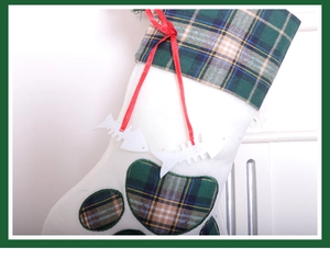 Detail view of white Christmas stocking with green plaid trim and cute fish bone pendants