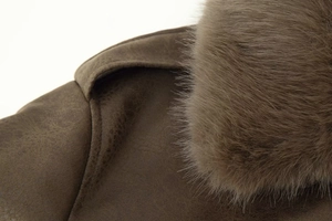 Close-up detail of smooth brown suede leather and soft faux fur collar on the jacket