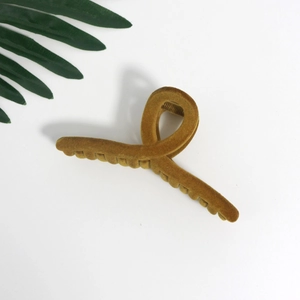 Detail of large velvet hair claw clip in mustard yellow with a soft flocked texture
