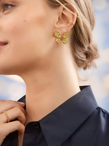 Detailed close-up of a gold hollow butterfly earring on a model with gold ear cuffs