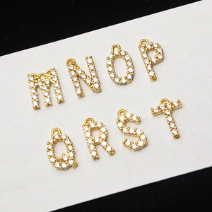 Close-up of gold-plated micro-pave letter charms M to T on white cardstock