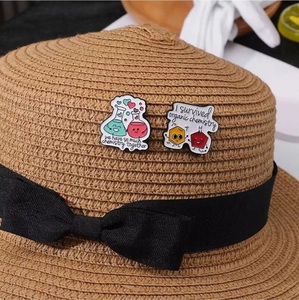 Chemistry enamel pins with humorous text displayed on a stylish brown straw hat ribbon