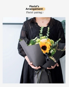 Detail of bouquet wrapped in black embossed dotted paper with sunflower and roses