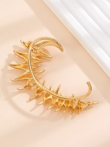 Macro view of a gold thorn ear cuff featuring a sharp geometric spike design