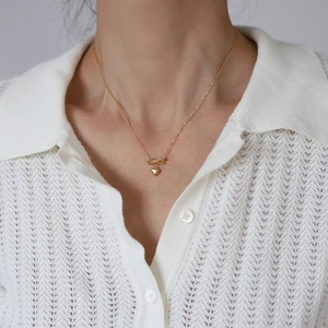 Elegant 18K gold-plated bow and heart pendant necklace worn on a white knitted top