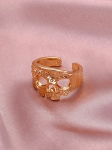 Dettaglio dell'anello teschio in oro rosa con rilievo su sfondo di seta rosa morbida
