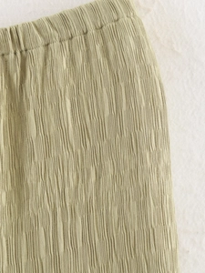 Détail du tissu texturé vert olive avec taille élastique et matière plissée