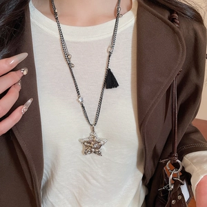Détail d'un pendentif étoile argenté avec cordon tressé et pompons noirs sur la chaîne