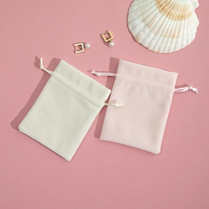 Flat lay of cream and pink plush drawstring jewelry pouches for gift packaging