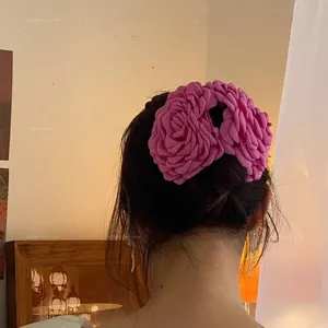 Dettaglio del fermaglio per capelli a rosa 3D rosa acceso indossato su uno chignon
