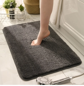 Close-up of thick absorbent dark grey plush bath mat on marble floor in a bathroom