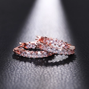 Macro shot of rose gold huggie hoop earrings with square-cut clear cubic zirconia stones